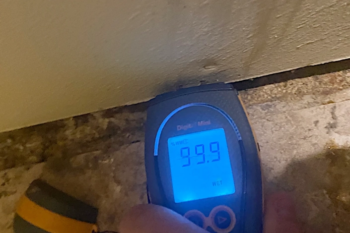 Water Damage Restoration in New Orleans. Wet Meter Reading Behind Baseboard. Flood Damage of Garage.